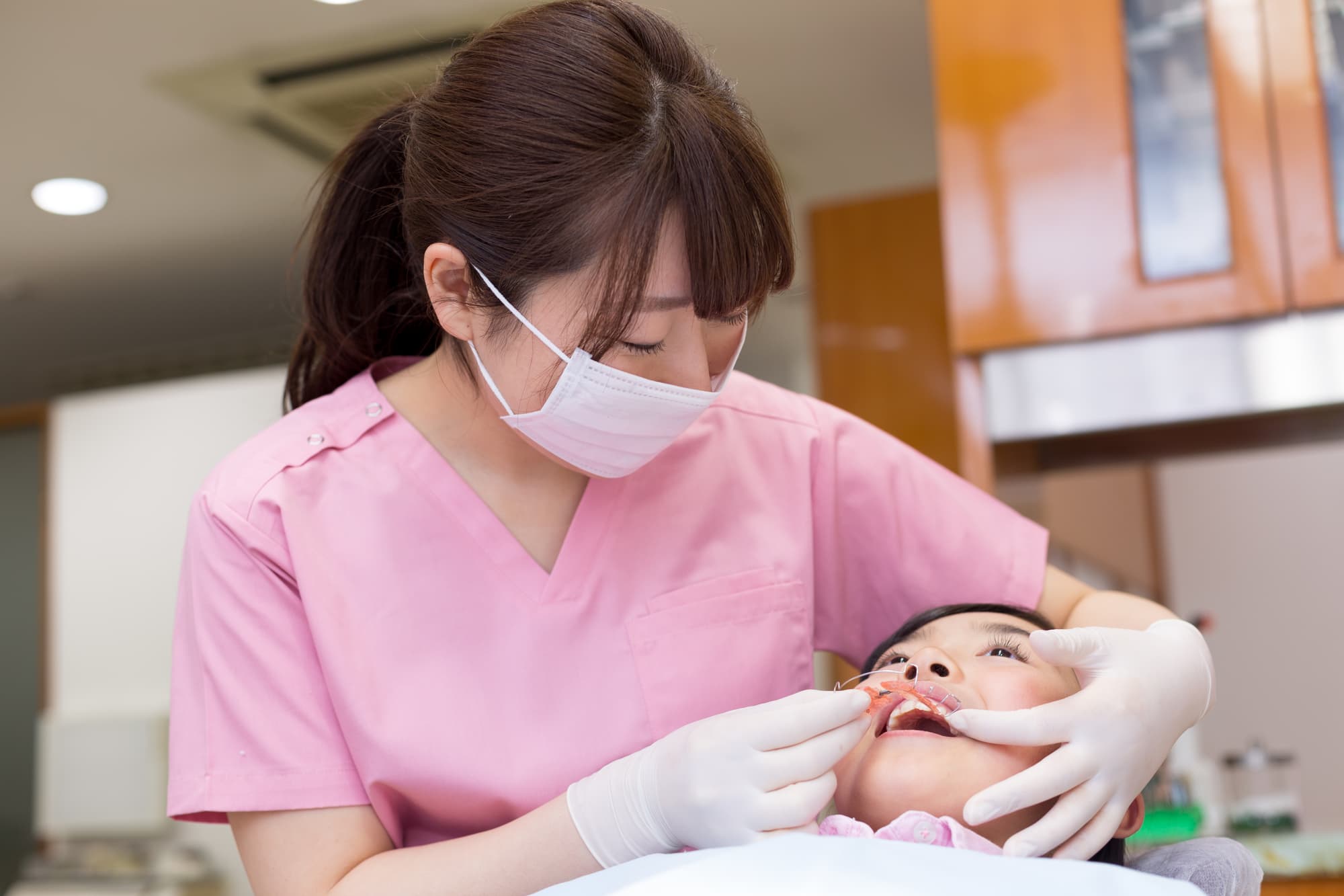 急速拡大装置を子供の口腔内に入れている歯科衛生士
