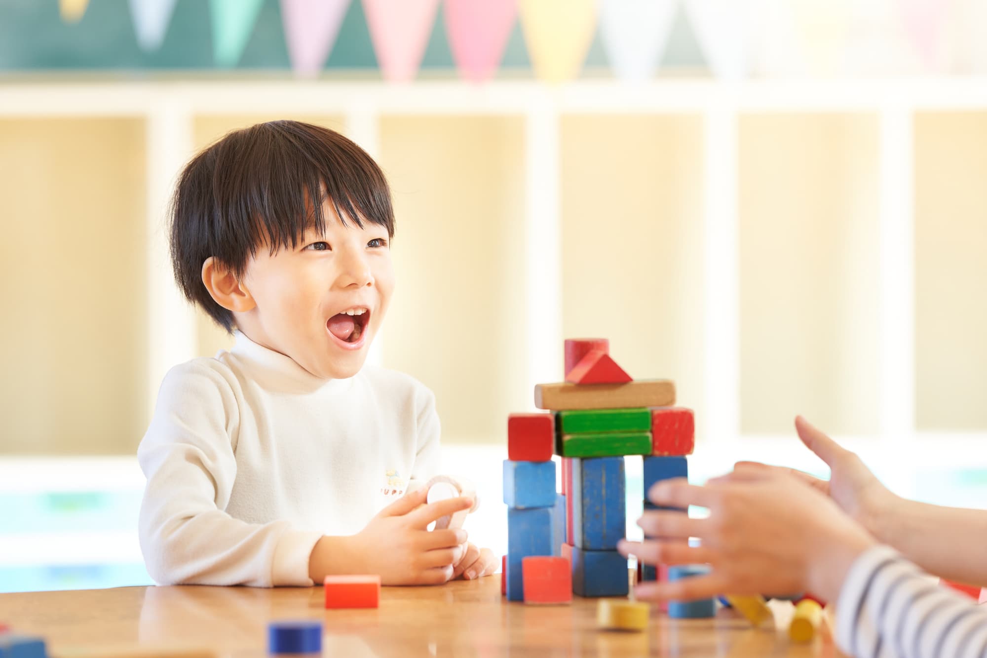 積み木で楽しそうに遊ぶ子ども
