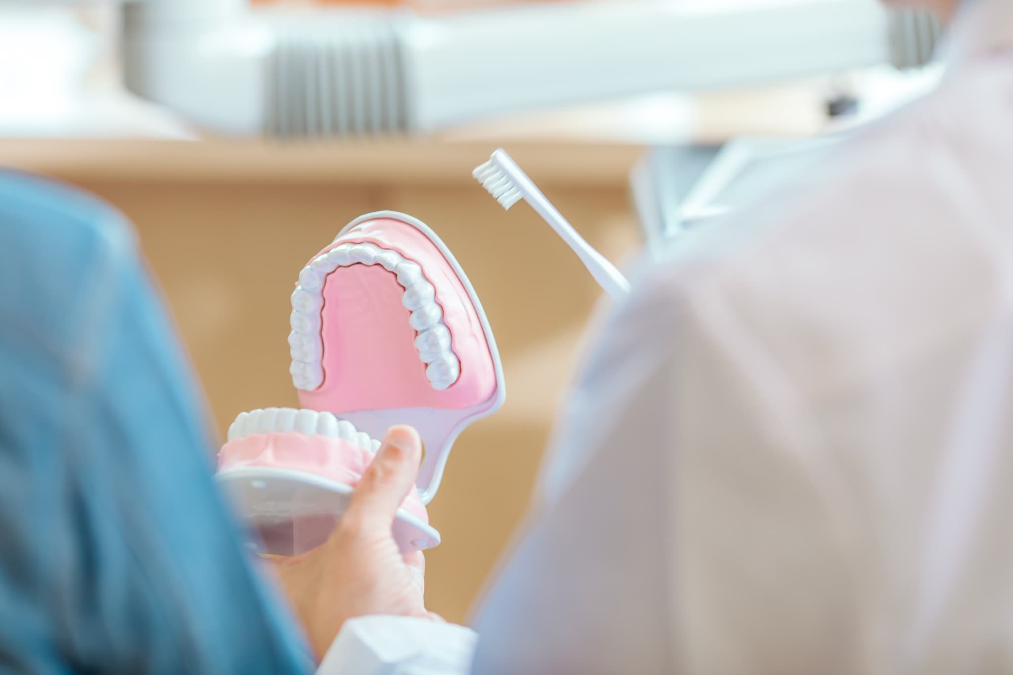 歯ブラシが届きにくいため奥歯は虫歯になりやすいことを説明する歯科医師