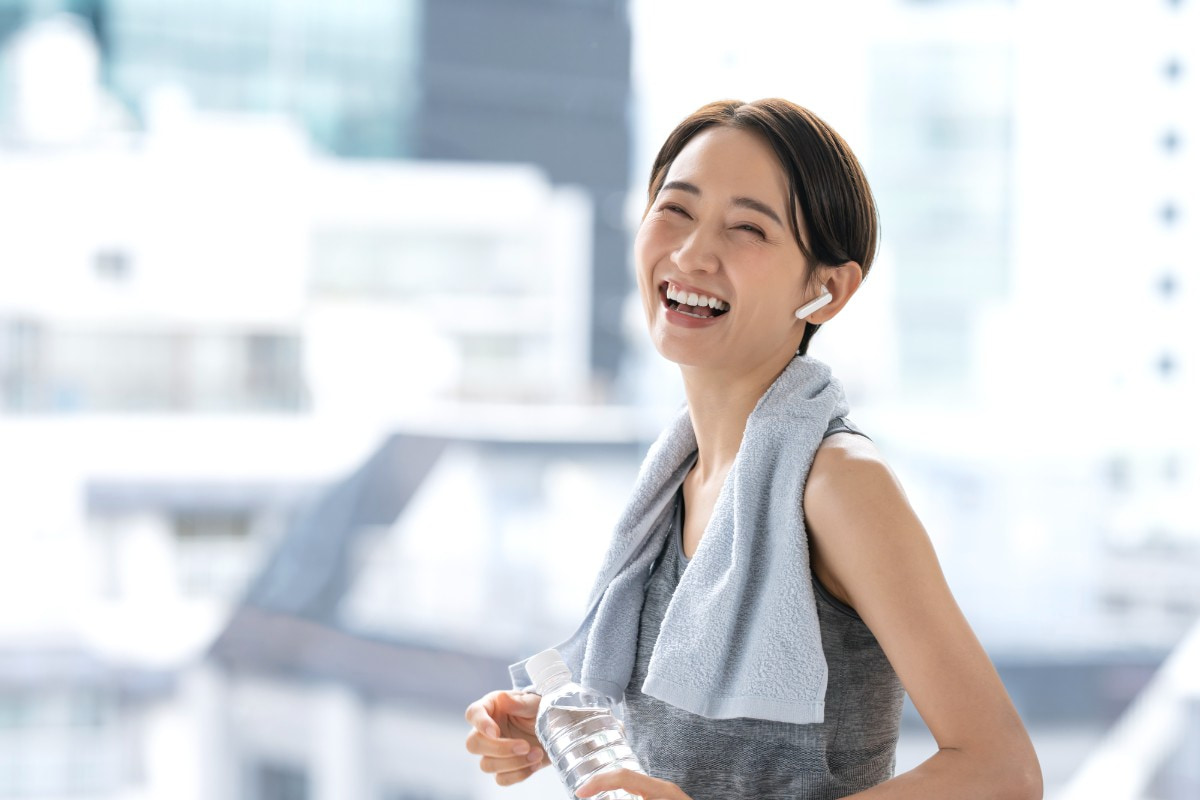 ランニングマシーンを笑顔で走っている女性
